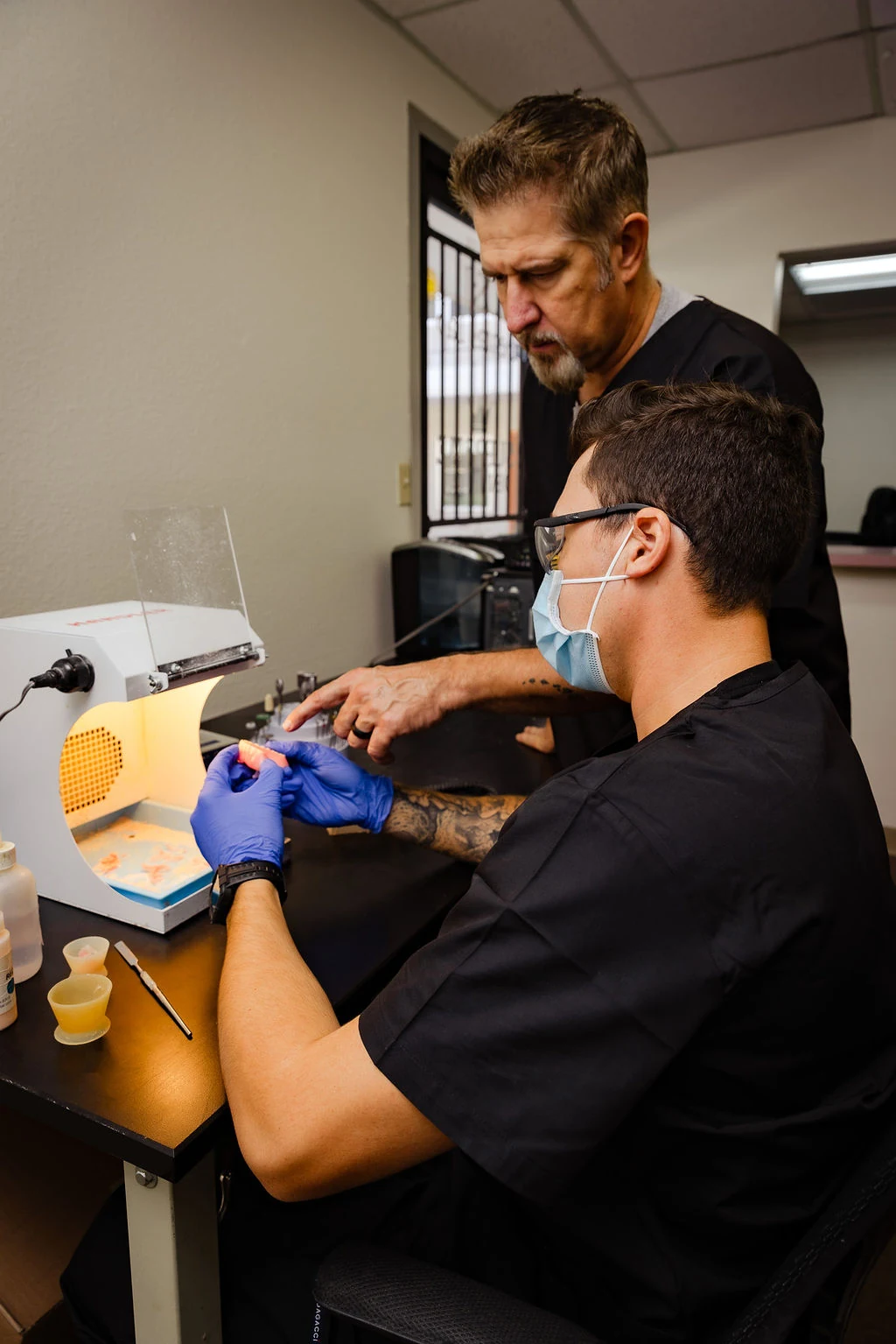 Father and son working together on a denture repair at the laboratory bench